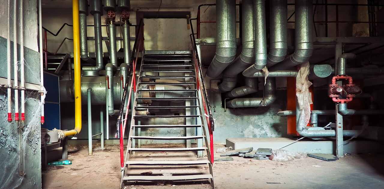 A steam boiler system in a warehouse with stairs.